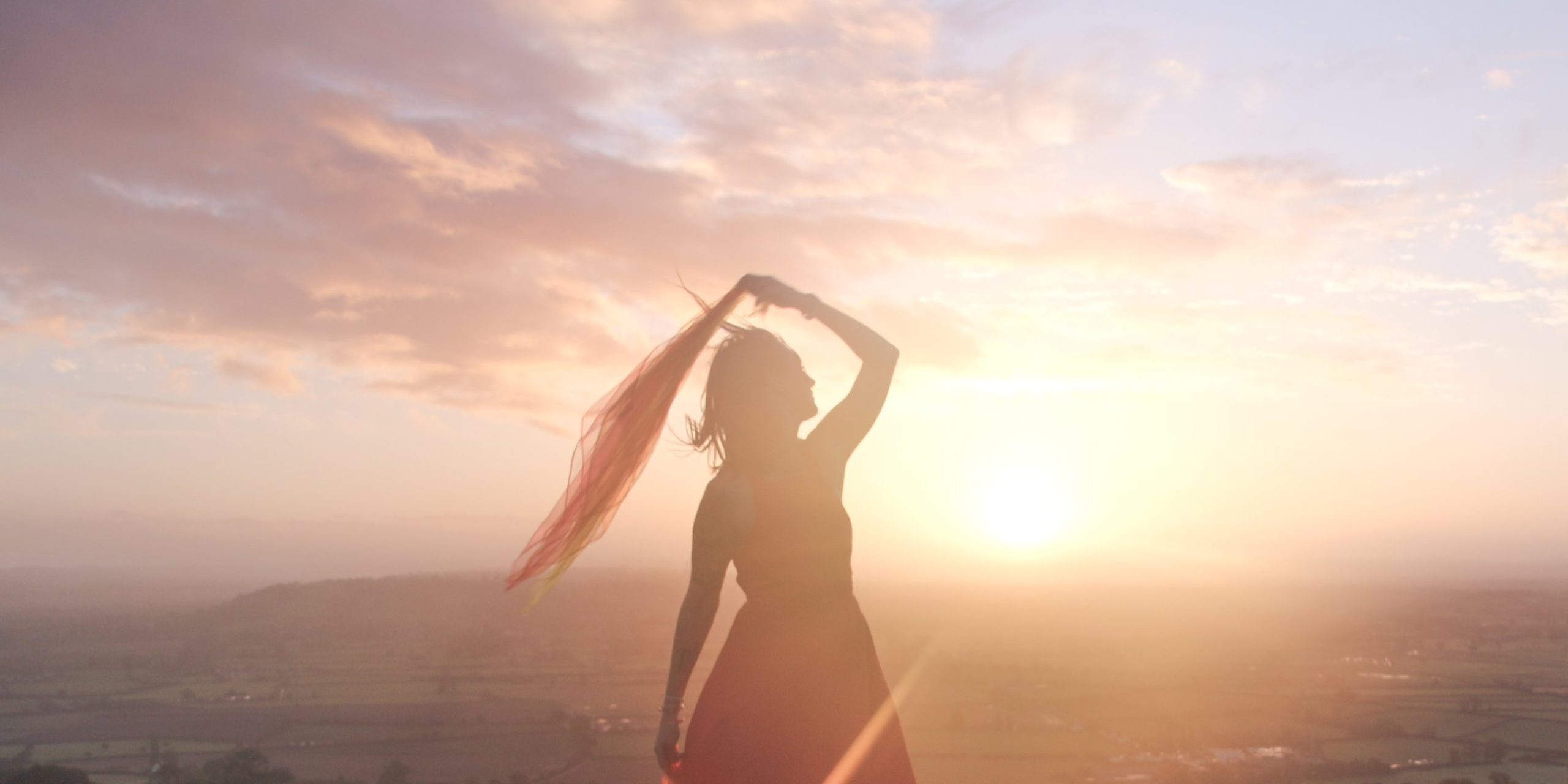 Femme dansant avec un voile au coucher du soleil